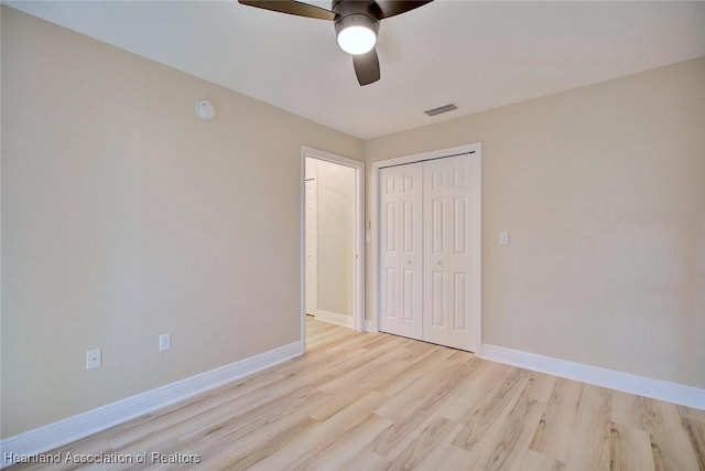 unfurnished bedroom featuring a closet, visible vents, baseboards, and wood finished floors