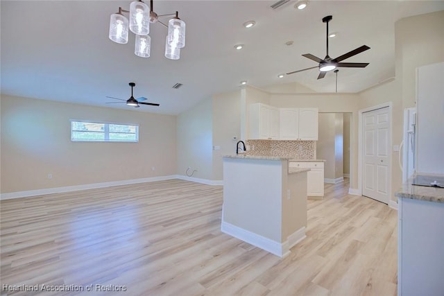 kitchen with light wood-style flooring, baseboards, vaulted ceiling, white cabinets, and backsplash