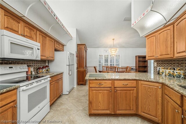 kitchen with light stone countertops, an inviting chandelier, kitchen peninsula, decorative light fixtures, and white appliances