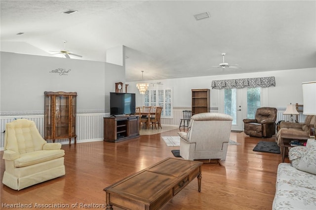 living room with french doors, ceiling fan with notable chandelier, lofted ceiling, and wood-type flooring