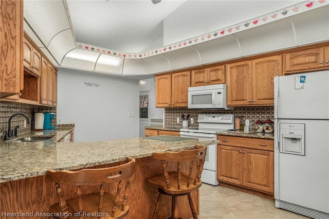 kitchen featuring kitchen peninsula, tasteful backsplash, a breakfast bar, white appliances, and sink