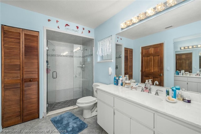 bathroom featuring tile patterned floors, vanity, toilet, and an enclosed shower