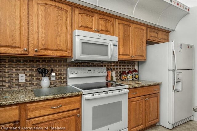 kitchen featuring decorative backsplash, light stone counters, white appliances, and light tile patterned floors