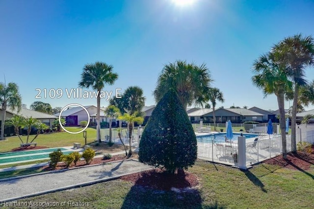 view of jungle gym featuring a community pool, fence, and a lawn