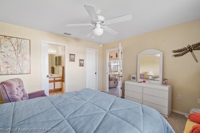 bedroom with baseboards, visible vents, ensuite bath, ceiling fan, and carpet flooring