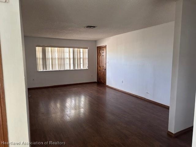 unfurnished room featuring dark hardwood / wood-style floors and a textured ceiling