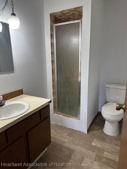 bathroom featuring vanity, toilet, and a shower with shower door