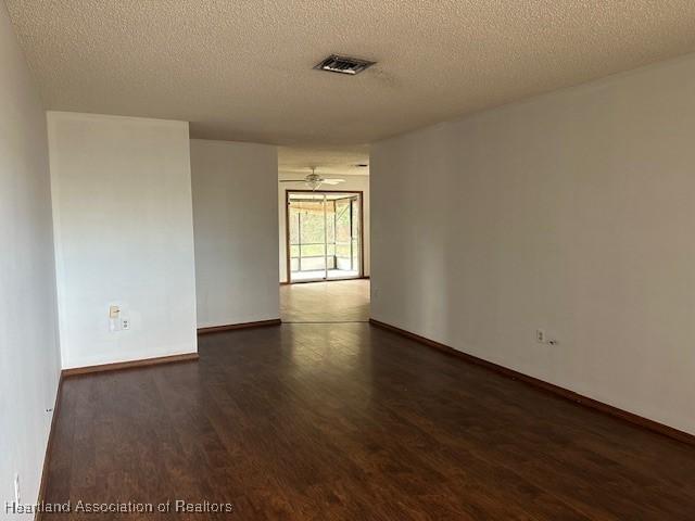 unfurnished room featuring ceiling fan, dark hardwood / wood-style floors, and a textured ceiling