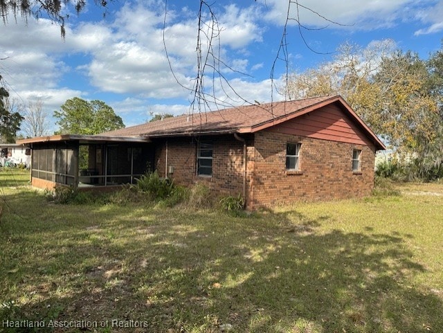 back of property featuring a sunroom and a lawn