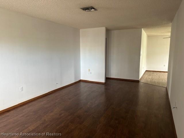 unfurnished room with dark hardwood / wood-style floors and a textured ceiling