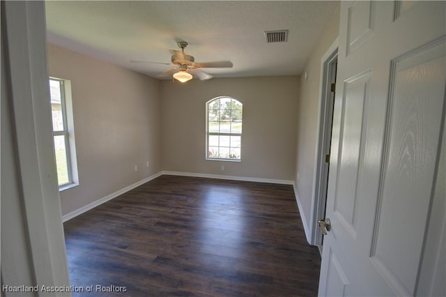 empty room with visible vents, ceiling fan, baseboards, dark wood finished floors, and a textured ceiling