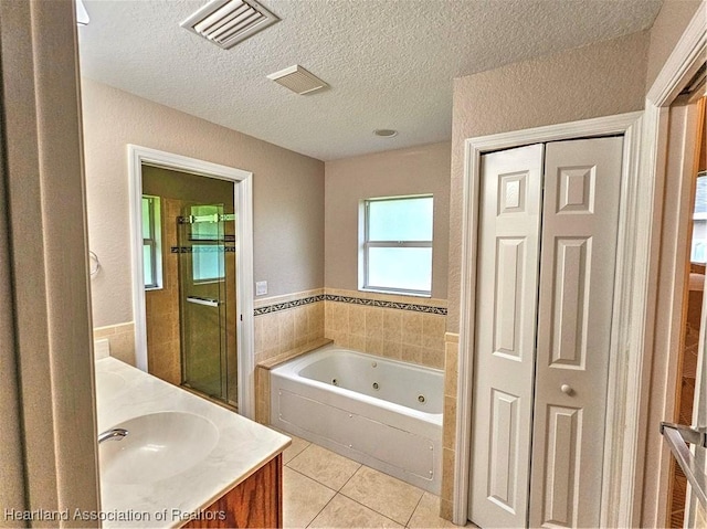 bathroom with tile patterned flooring, visible vents, vanity, a whirlpool tub, and a textured ceiling