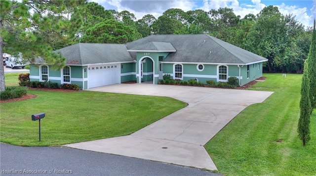 ranch-style home featuring stucco siding, an attached garage, concrete driveway, and a front lawn