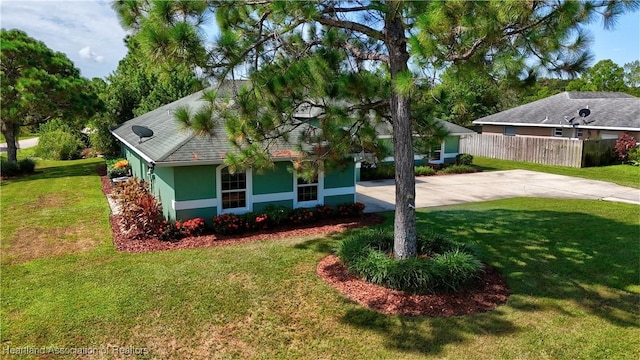 view of front of home with stucco siding, concrete driveway, a front yard, and fence