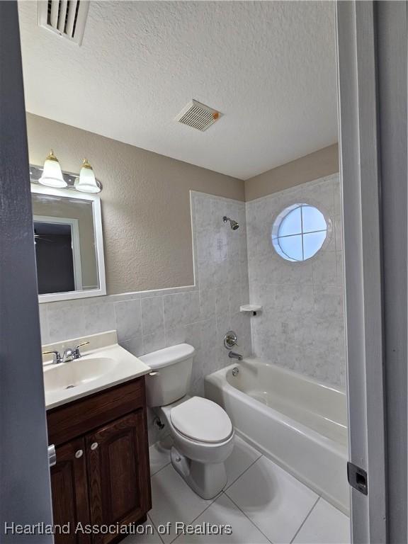 bathroom featuring visible vents, tile walls, bathtub / shower combination, a textured ceiling, and vanity