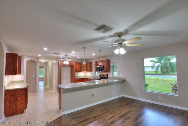 kitchen featuring visible vents, appliances with stainless steel finishes, a peninsula, arched walkways, and a sink