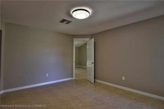 unfurnished room featuring visible vents, baseboards, a textured ceiling, and tile patterned flooring