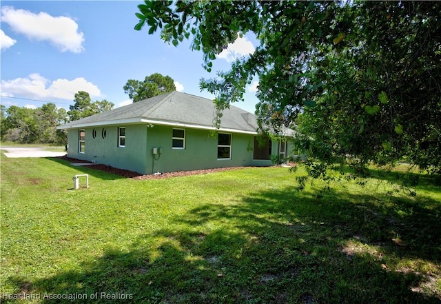 back of property featuring a lawn and stucco siding