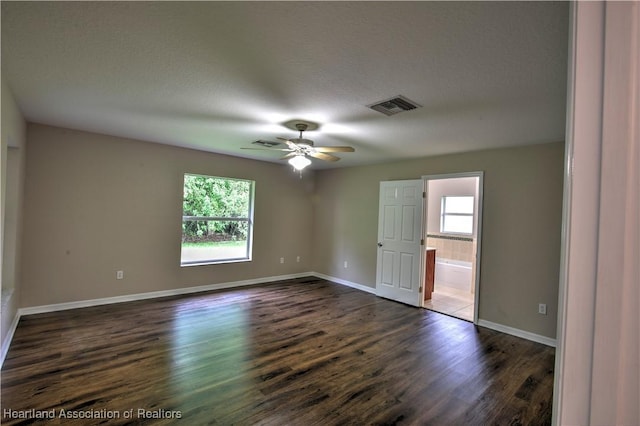 unfurnished room with visible vents, dark wood-type flooring, and a healthy amount of sunlight