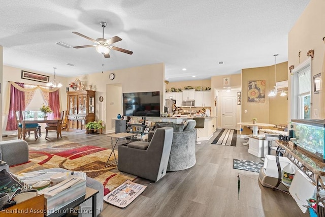297 NE Glentry Ave NE, Port St Lucie, FL 34983 - living room with a ceiling fan, wood finished floors, plenty of natural light, a textured ceiling, and a chandelier