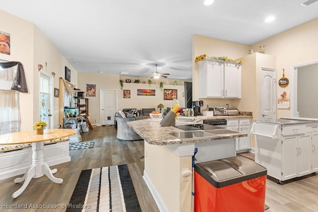 297 NE Glentry Ave NE, Port St Lucie, FL 34983 - kitchen with a peninsula, light wood-style flooring, white cabinetry, and recessed lighting