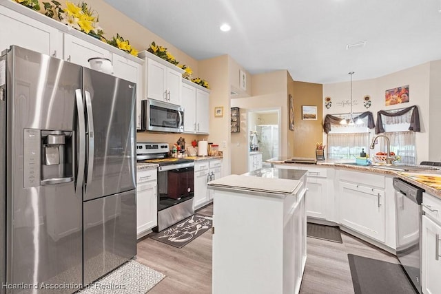 297 NE Glentry Ave NE, Port St Lucie, FL 34983 - kitchen with appliances with stainless steel finishes, a center island, light wood finished floors, white cabinets, and light countertops