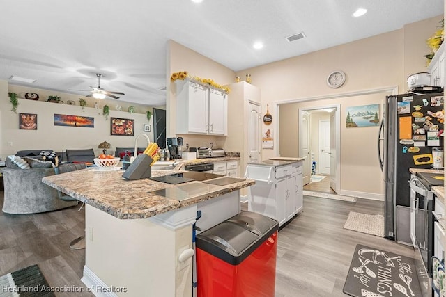 297 NE Glentry Ave NE, Port St Lucie, FL 34983 - kitchen with a peninsula, white cabinetry, ceiling fan, wood finished floors, and a breakfast bar area