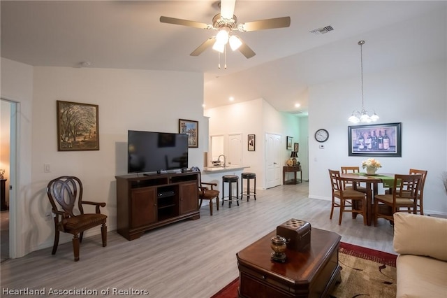 living room with sink, light hardwood / wood-style floors, and ceiling fan with notable chandelier