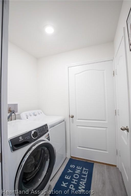 clothes washing area featuring washer and clothes dryer and light hardwood / wood-style flooring