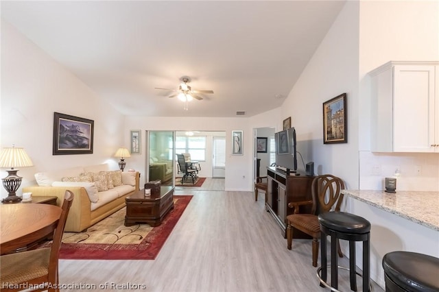 living room with ceiling fan, light wood-type flooring, and lofted ceiling