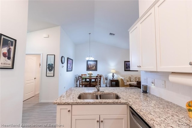 kitchen featuring light stone countertops, vaulted ceiling, sink, white cabinets, and hanging light fixtures