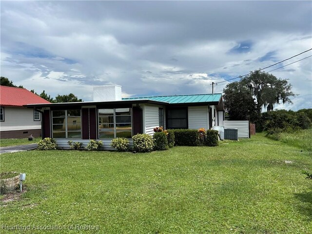 11 Mockingbird Rd, Lake Placid, FL 33852 - single story home featuring a chimney, a metal roof, a front yard, and a sunroom