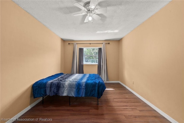 bedroom with ceiling fan, hardwood / wood-style floors, and a textured ceiling