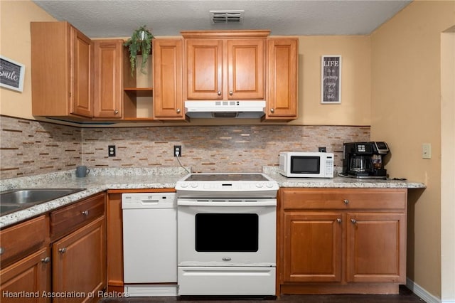 kitchen with a textured ceiling, white appliances, tasteful backsplash, and light stone counters