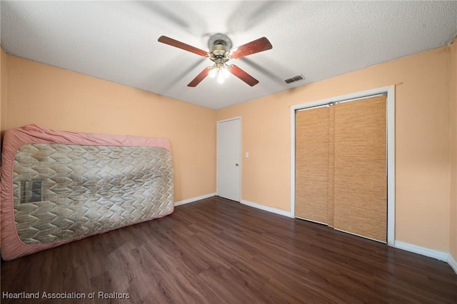 unfurnished bedroom featuring a textured ceiling, a closet, ceiling fan, and dark hardwood / wood-style floors