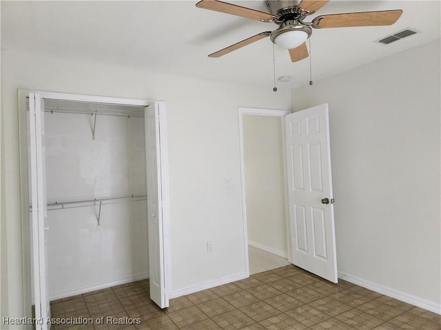 unfurnished bedroom with a closet, tile patterned floors, visible vents, baseboards, and ceiling fan