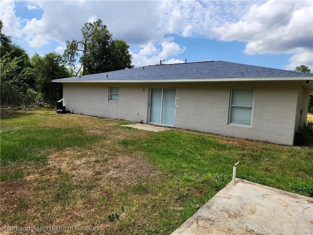 back of property with a yard, stucco siding, and a patio