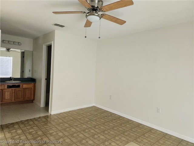 unfurnished room featuring a sink, baseboards, a ceiling fan, and visible vents