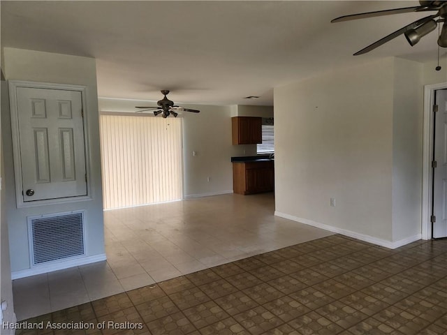 unfurnished living room featuring visible vents, baseboards, and a ceiling fan