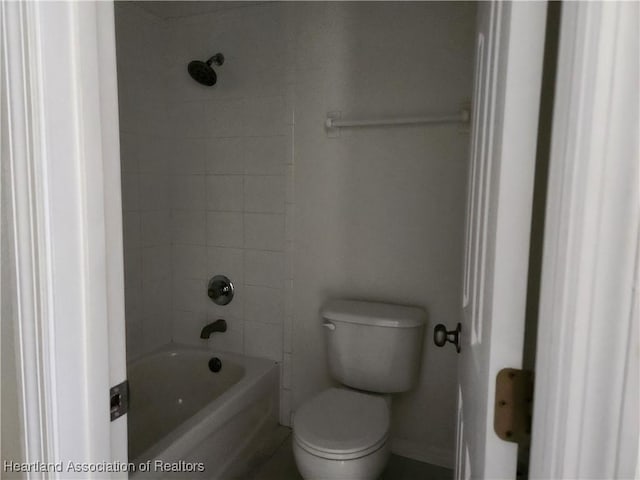 bathroom with toilet, washtub / shower combination, and baseboards