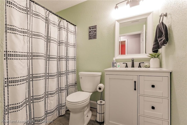 bathroom featuring a textured ceiling, vanity, toilet, and curtained shower