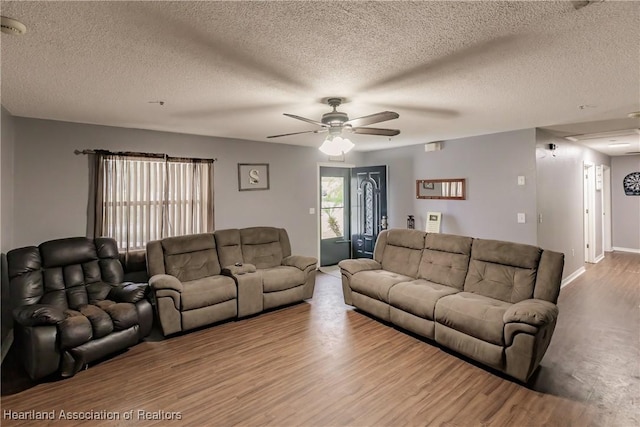 living room featuring ceiling fan, hardwood / wood-style floors, and a textured ceiling