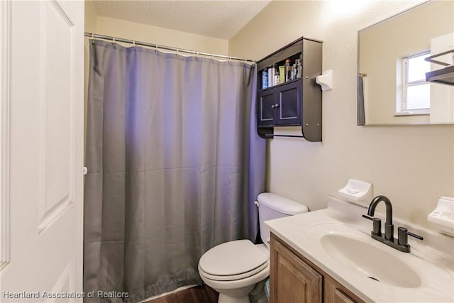 bathroom with vanity, a textured ceiling, toilet, and walk in shower