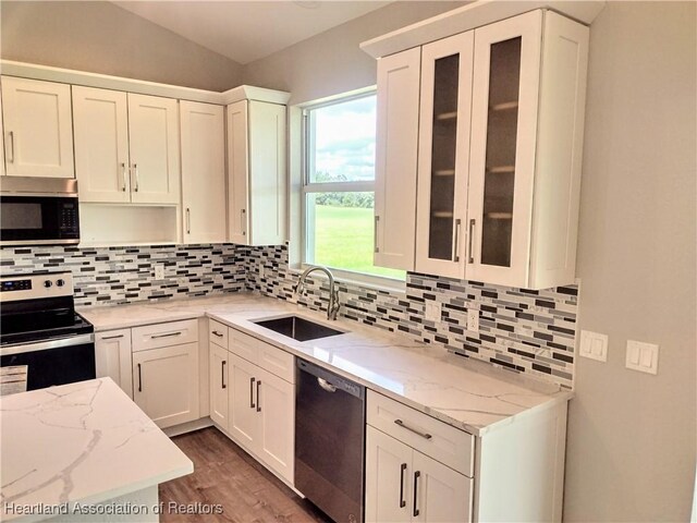 kitchen featuring light stone countertops, sink, tasteful backsplash, white cabinets, and appliances with stainless steel finishes