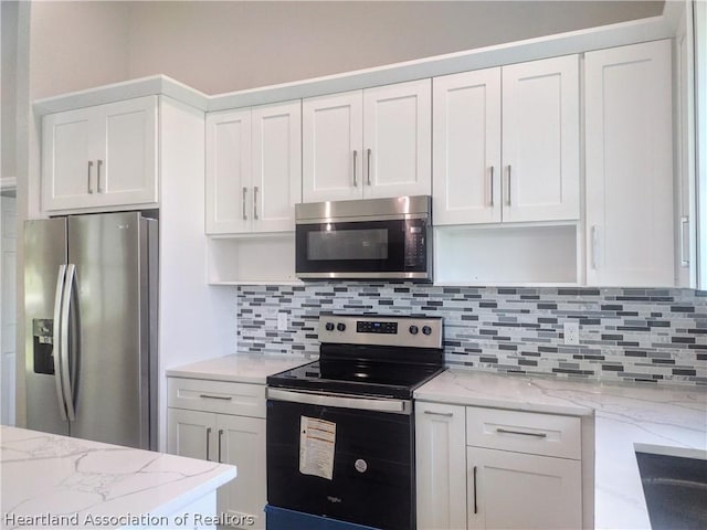 kitchen with backsplash, white cabinetry, stainless steel appliances, and light stone counters