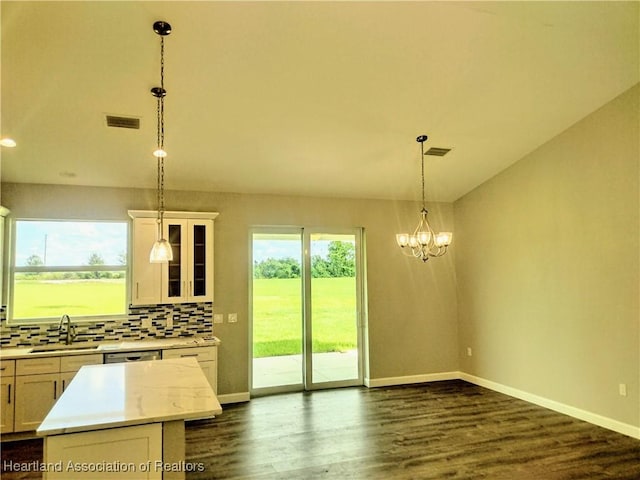 kitchen featuring sink, hanging light fixtures, a kitchen island, backsplash, and white cabinets