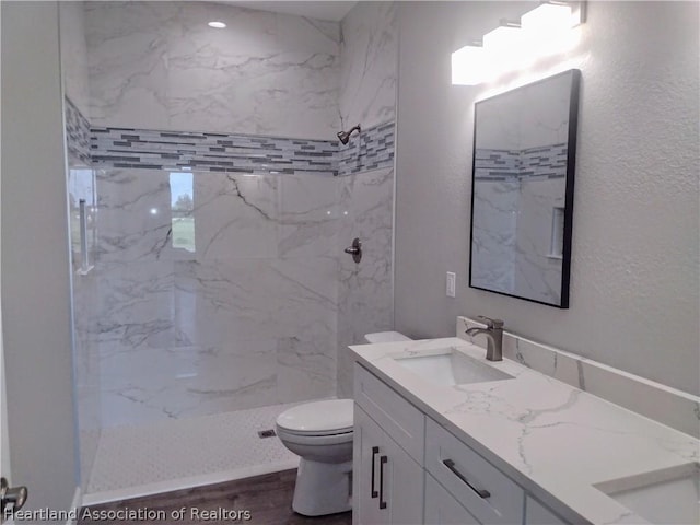 bathroom featuring toilet, vanity, and tiled shower