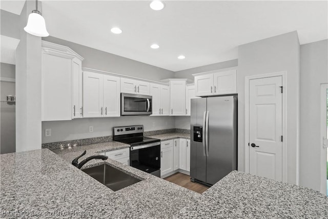 kitchen with light stone countertops, sink, pendant lighting, white cabinets, and appliances with stainless steel finishes