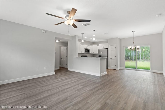 unfurnished living room featuring ceiling fan with notable chandelier and hardwood / wood-style flooring