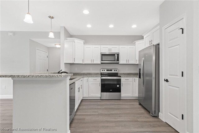 kitchen with light stone countertops, kitchen peninsula, decorative light fixtures, white cabinets, and appliances with stainless steel finishes